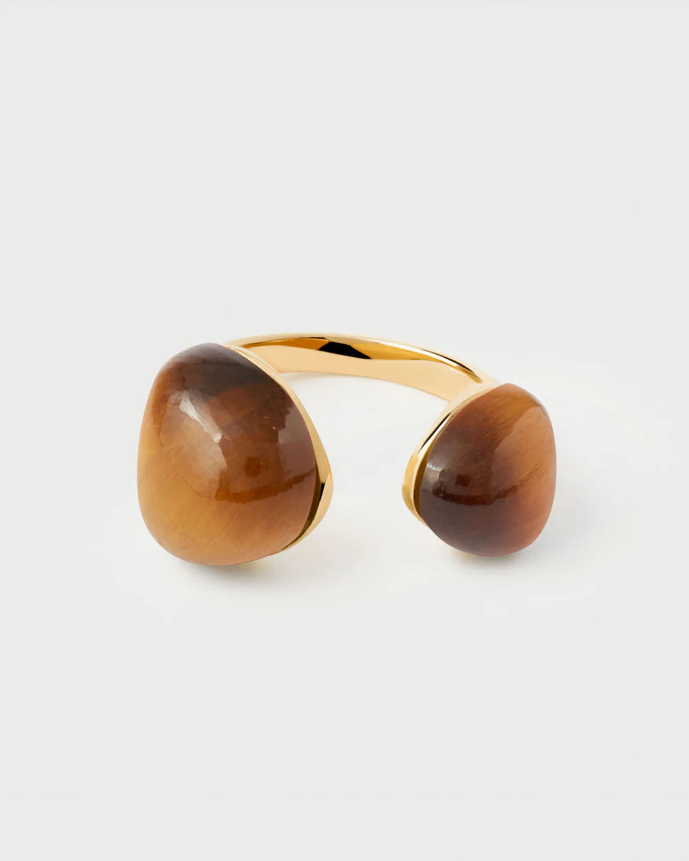 Gold ring with two large brown stones on a light gray background