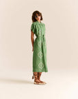 Woman wearing a green dress with white patterns on a beige background