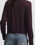 Person wearing a dark brown sweater and blue jeans on a white background