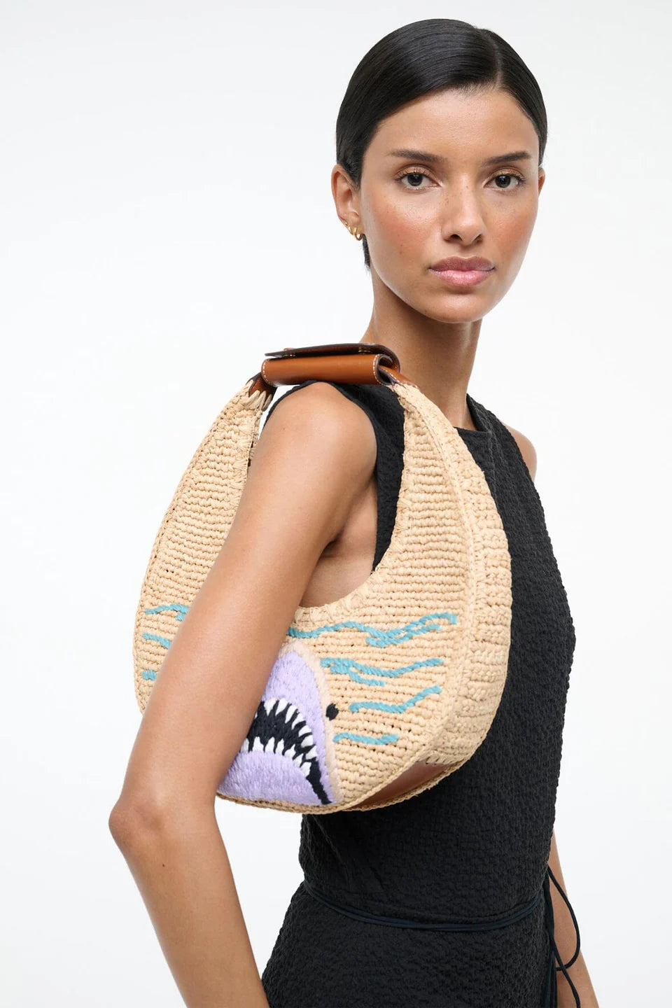 Woman wearing a straw bag with shark design on a white background