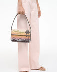 Person holding a handbag with a scenic design on a white background