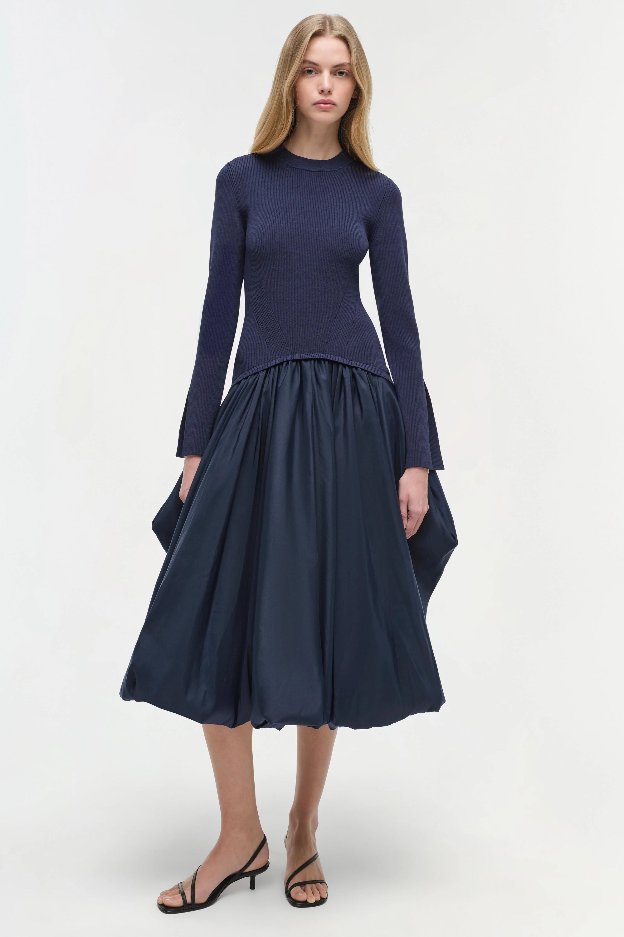 Woman wearing a navy blue dress with a white background front