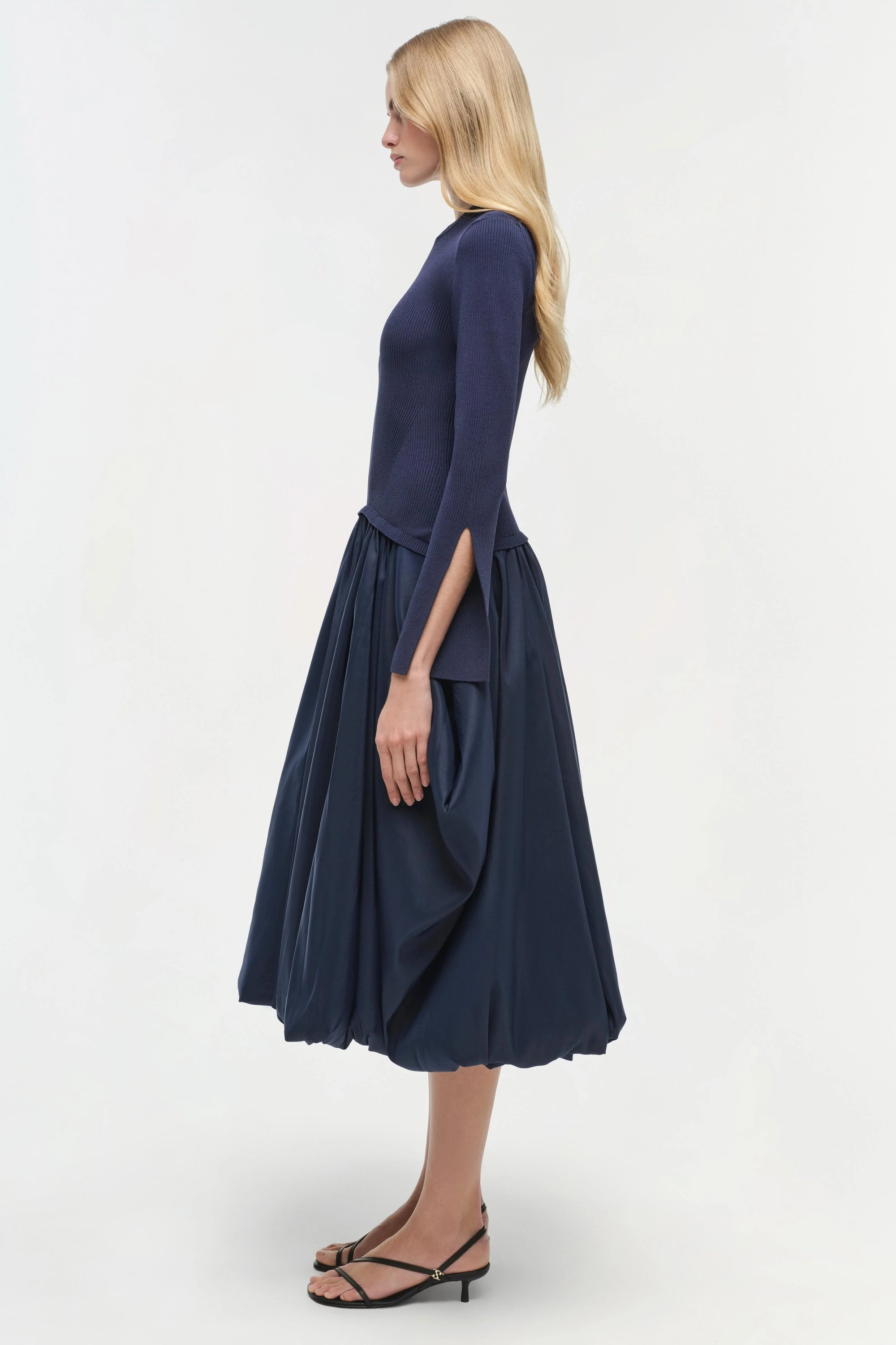 Woman wearing a navy blue dress on a white background side