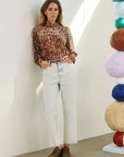 model wearing dapple doe printed top and jeans with art paper mache balls in the background