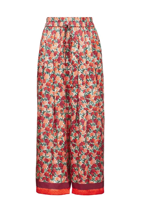A pair of high-waisted, wide-leg cropped pants featuring an all-over red and orange floral print with green leaves, finished with a solid red drawstring waist and a matching red hem.