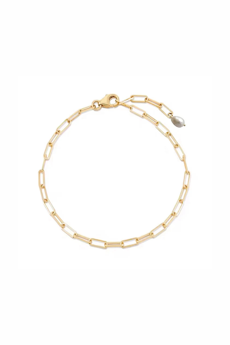 A delicate gold chain bracelet with elongated paperclip links, a lobster clasp, and a small teardrop pearl accent, displayed on a clean white background.