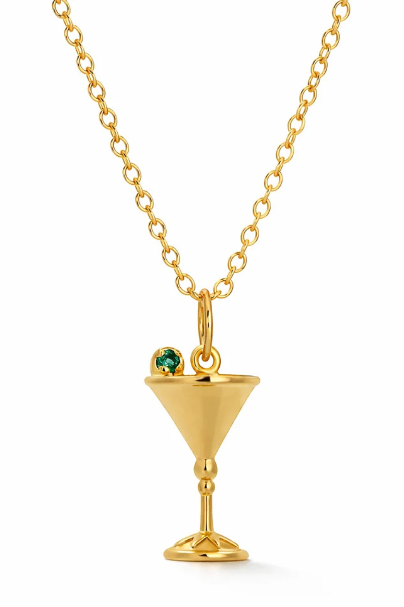 A gold chain necklace featuring a martini glass pendant with a small green gemstone garnish, shown against a plain white background.