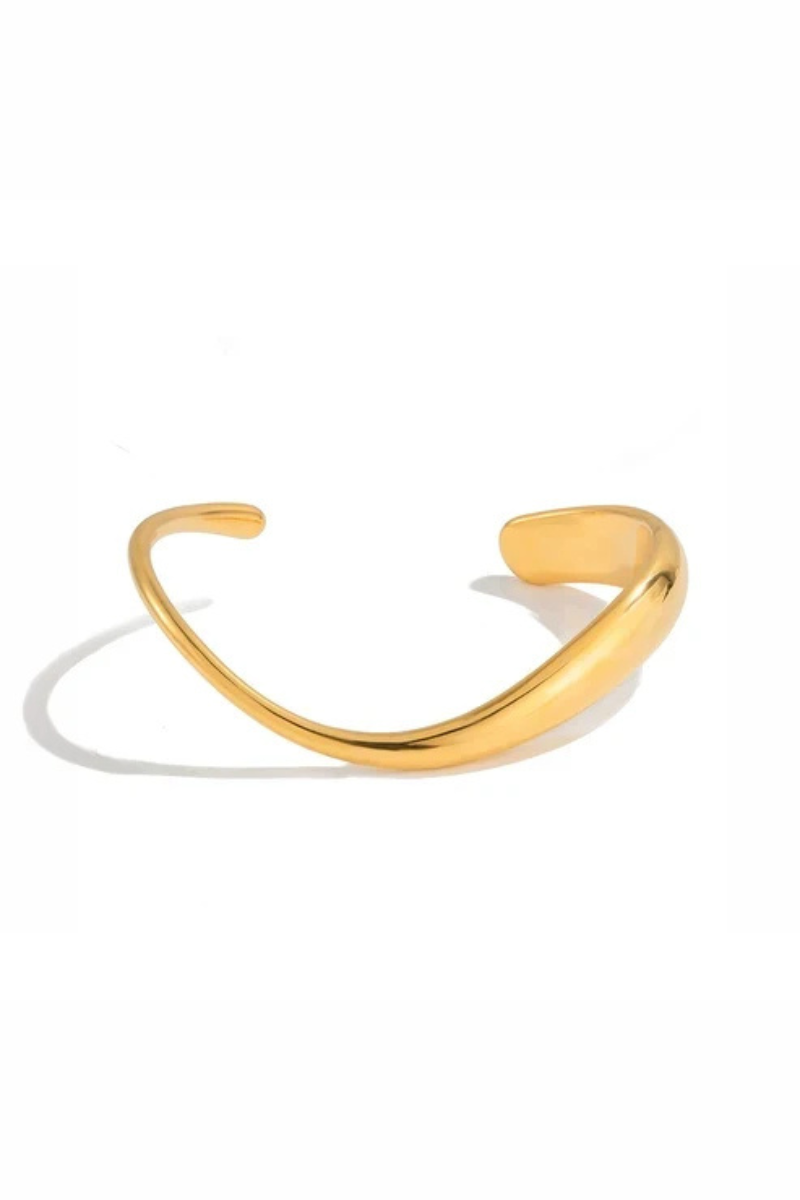 A polished gold-toned metal cuff bracelet with a smooth, curved design, displayed on a clean white background with a soft shadow.