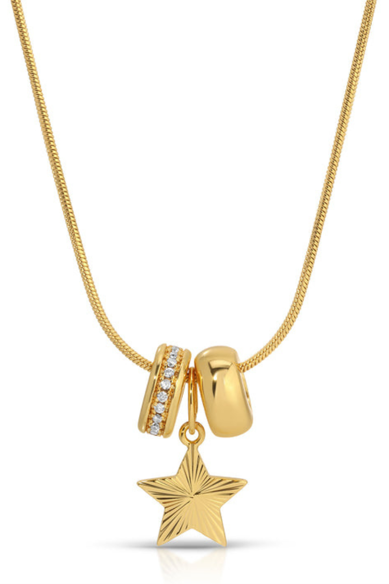 A gold necklace featuring three charms: a textured star pendant, a polished bead, and a spacer bead set with small clear stones, shown on a white background.