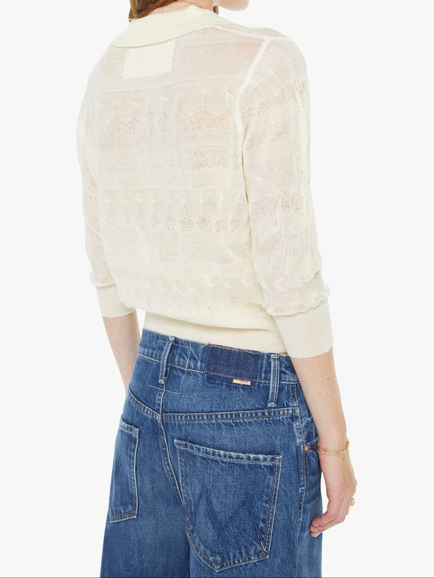 Woman wearing a cream blouse and blue jeans on a white background