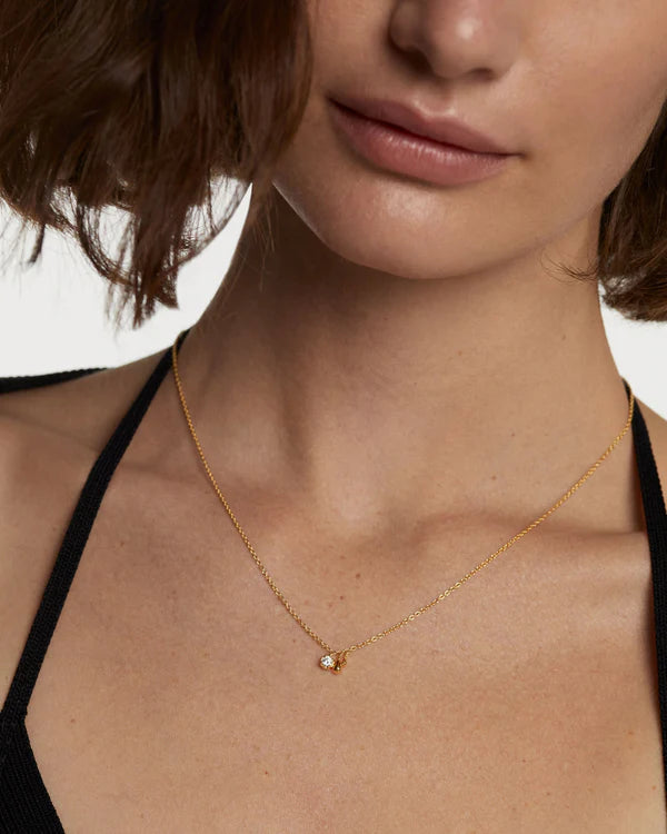Close-up of a person wearing a gold necklace with a small pendant front view