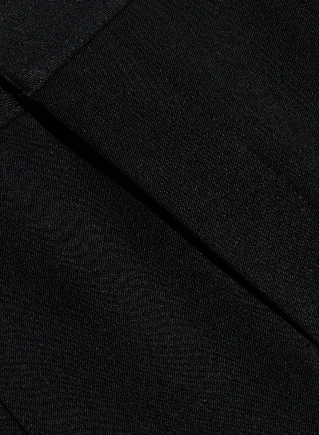 Close-up of a black fabric surface with a diagonal seam and fine woven texture.