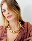 Woman wearing a gold necklace against a plain background