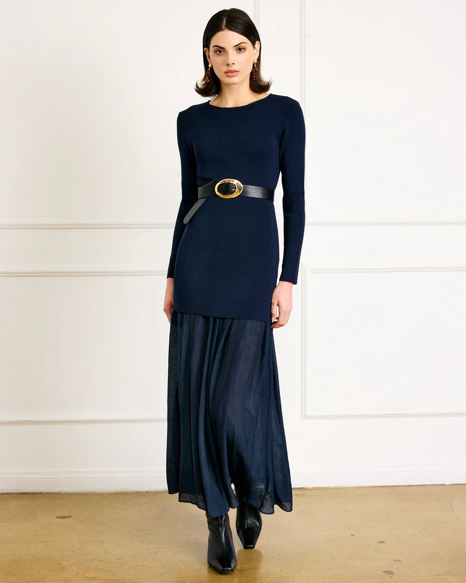Woman wearing a navy blue dress with a belt in a minimalistic setting
