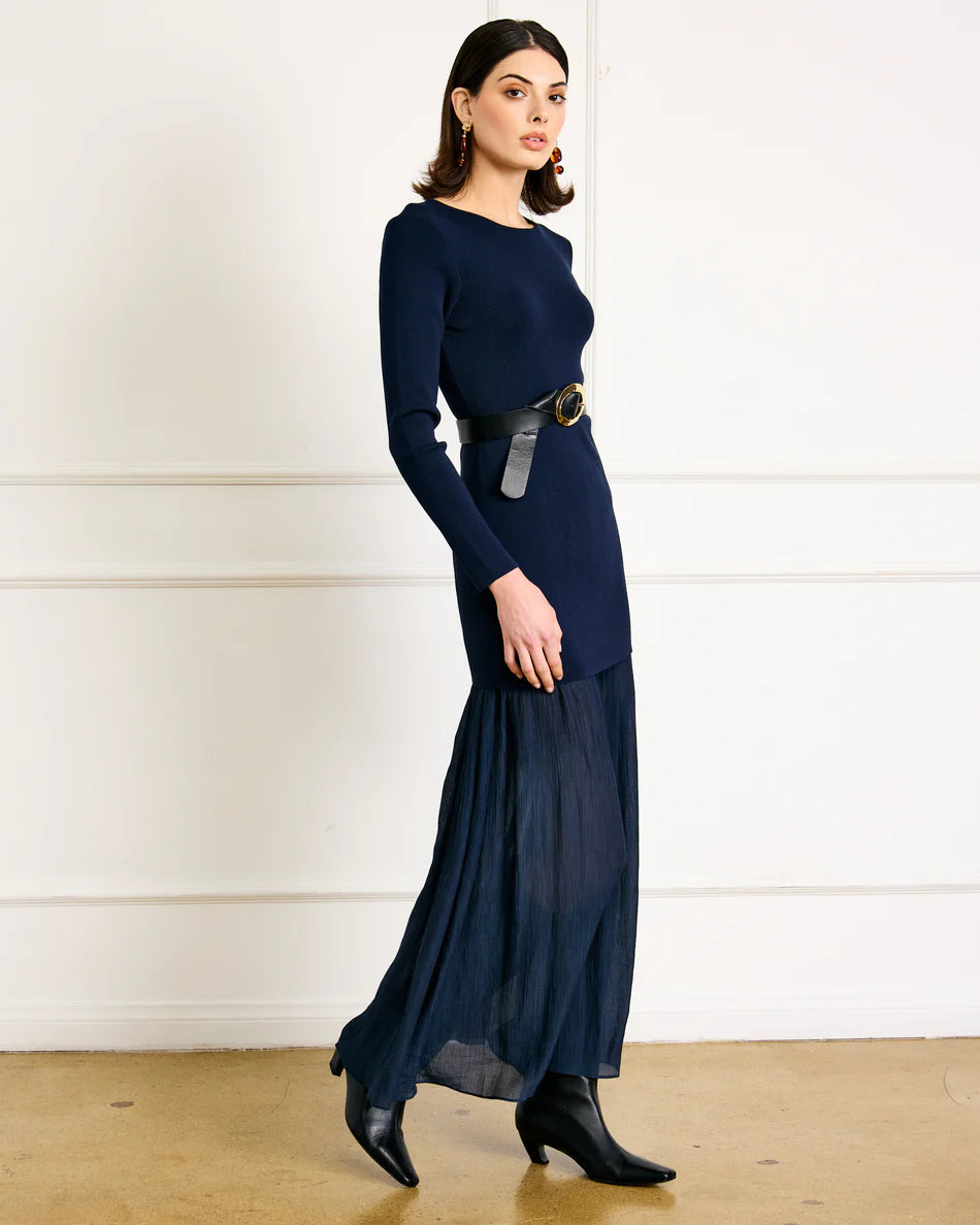 Woman wearing a navy blue dress with a belt in a minimalistic setting