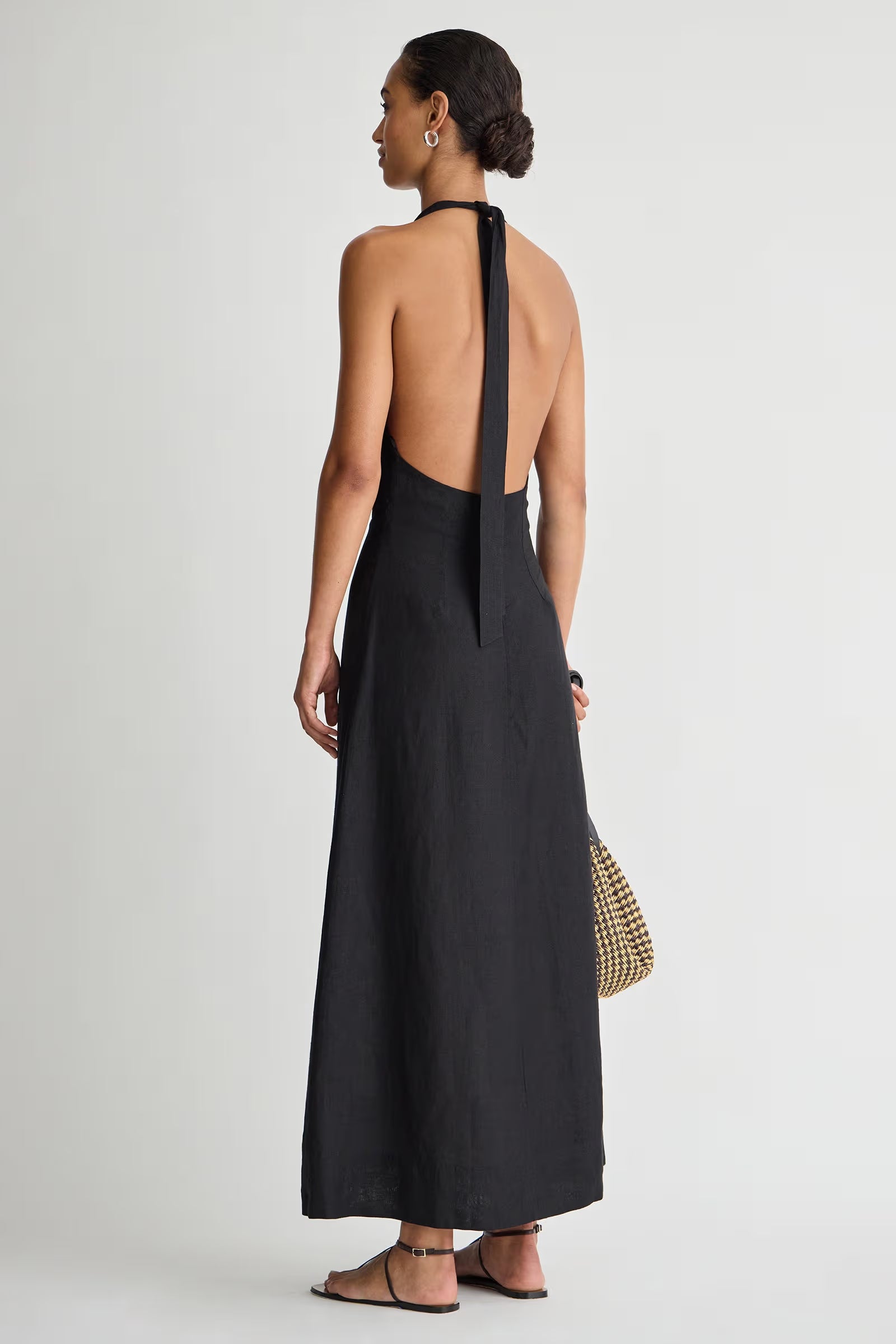 Woman wearing a black halter neck dress on a white background