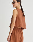 Woman wearing a brown sleeveless top and shorts set on a white background