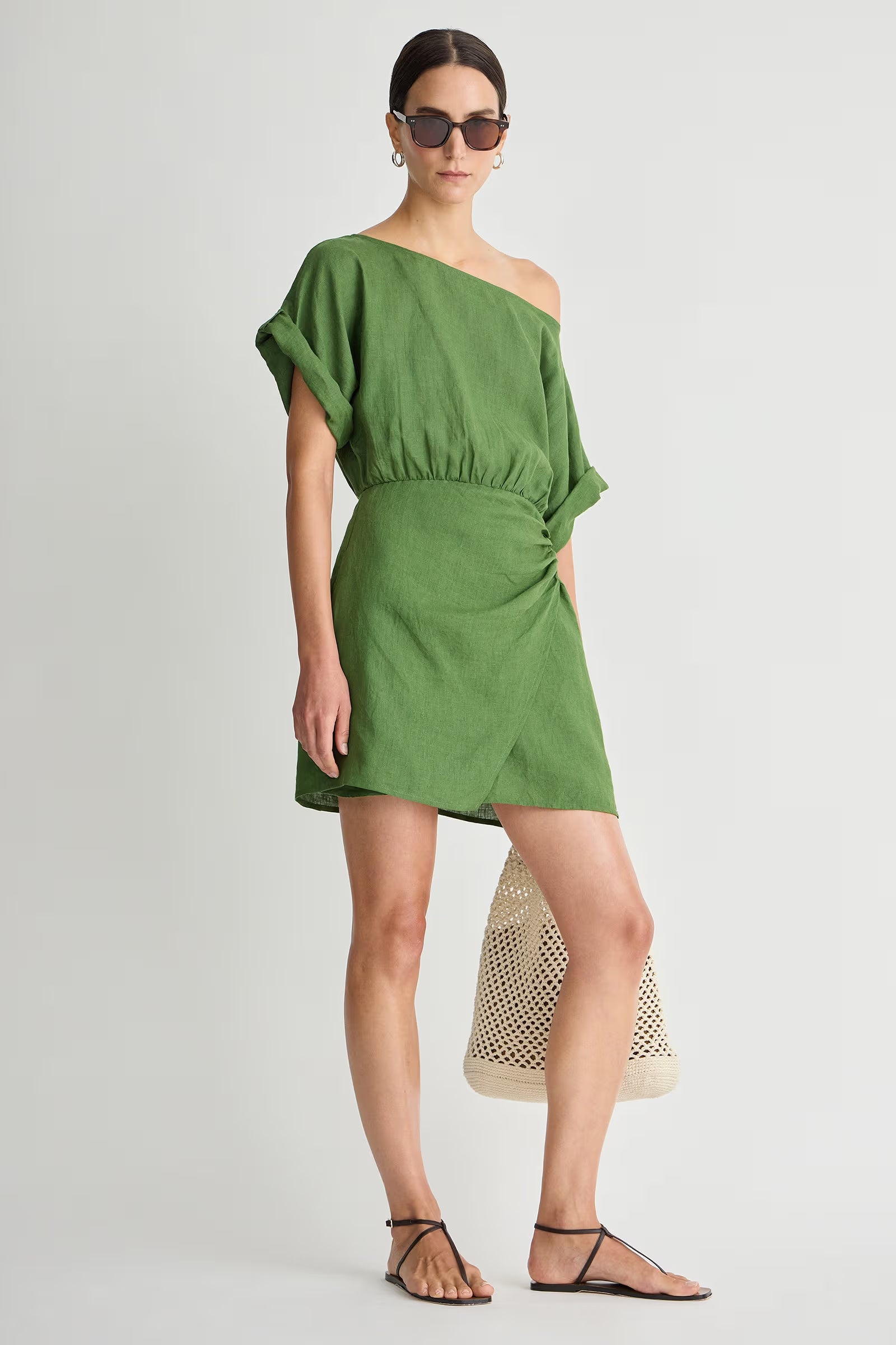 Woman wearing a green one-shoulder dress on a white background