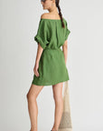 Woman wearing a green off-shoulder dress on a white background