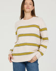 Woman wearing a cream sweater with yellow stripes on a white background