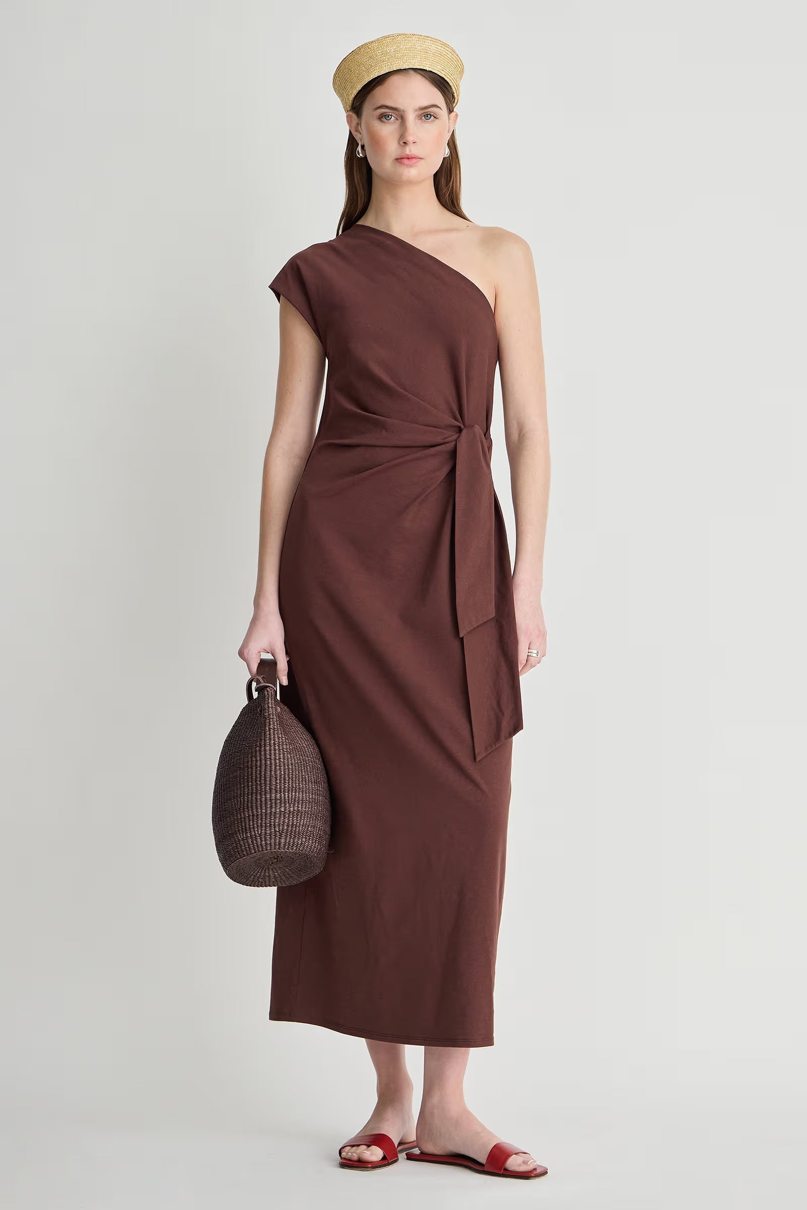 model wearing a one shoulder brown dress with a white background