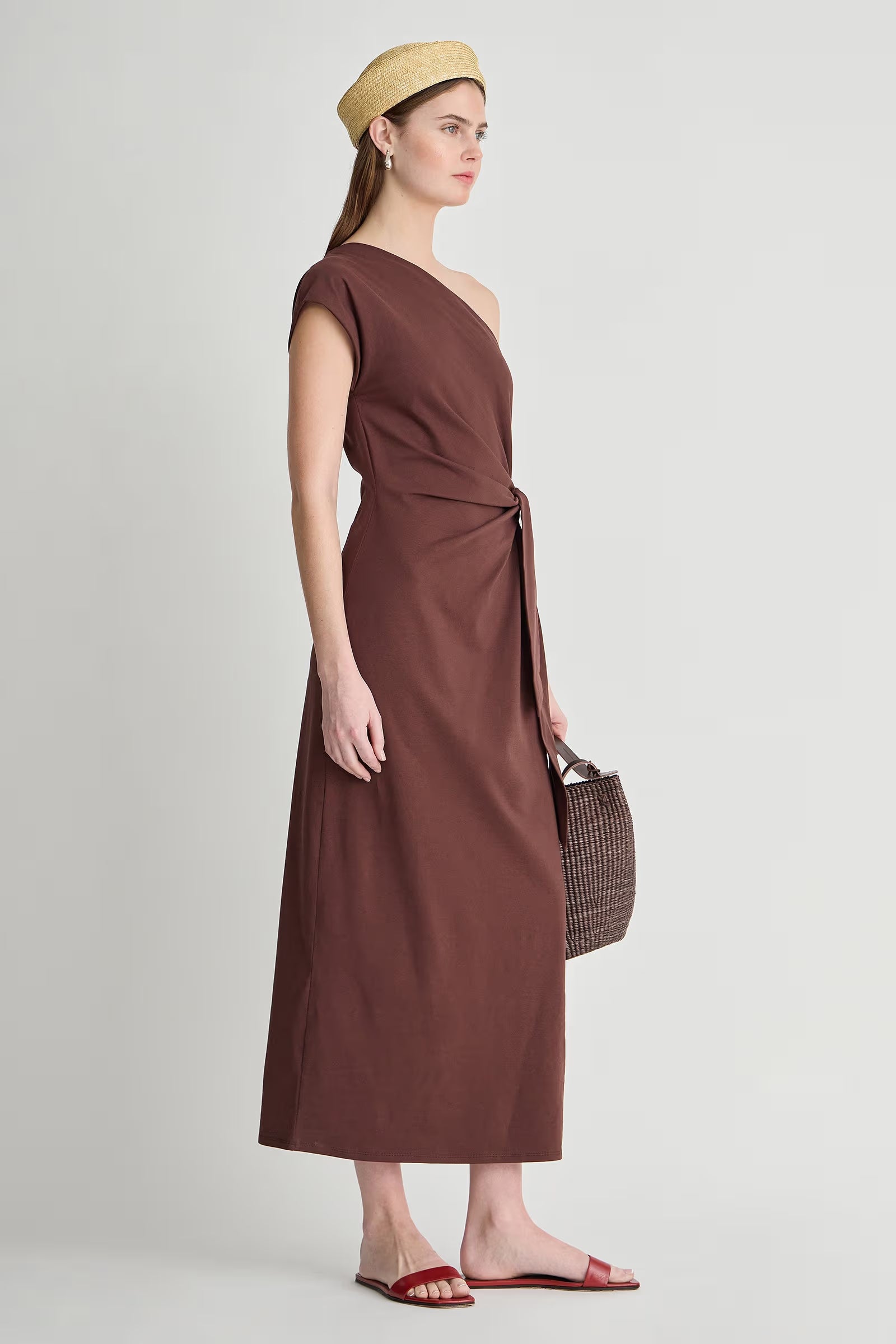 model wearing a one shoulder brown dress with a white background