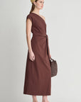model wearing a one shoulder brown dress with a white background