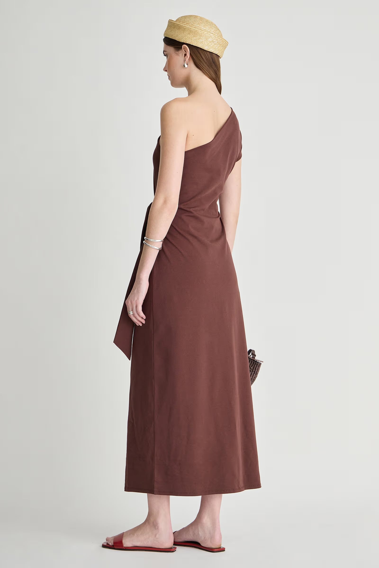 model wearing a one shoulder brown dress with a white background