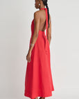 Woman wearing a red halter neck dress with a white background