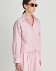 Woman wearing a pink outfit with sunglasses on a plain background