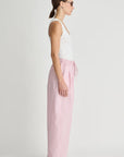 Woman wearing a white tank top and pink pants on a white background