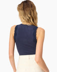 model wearing a high neck lace trim tank with white bottoms on a white background from the back
