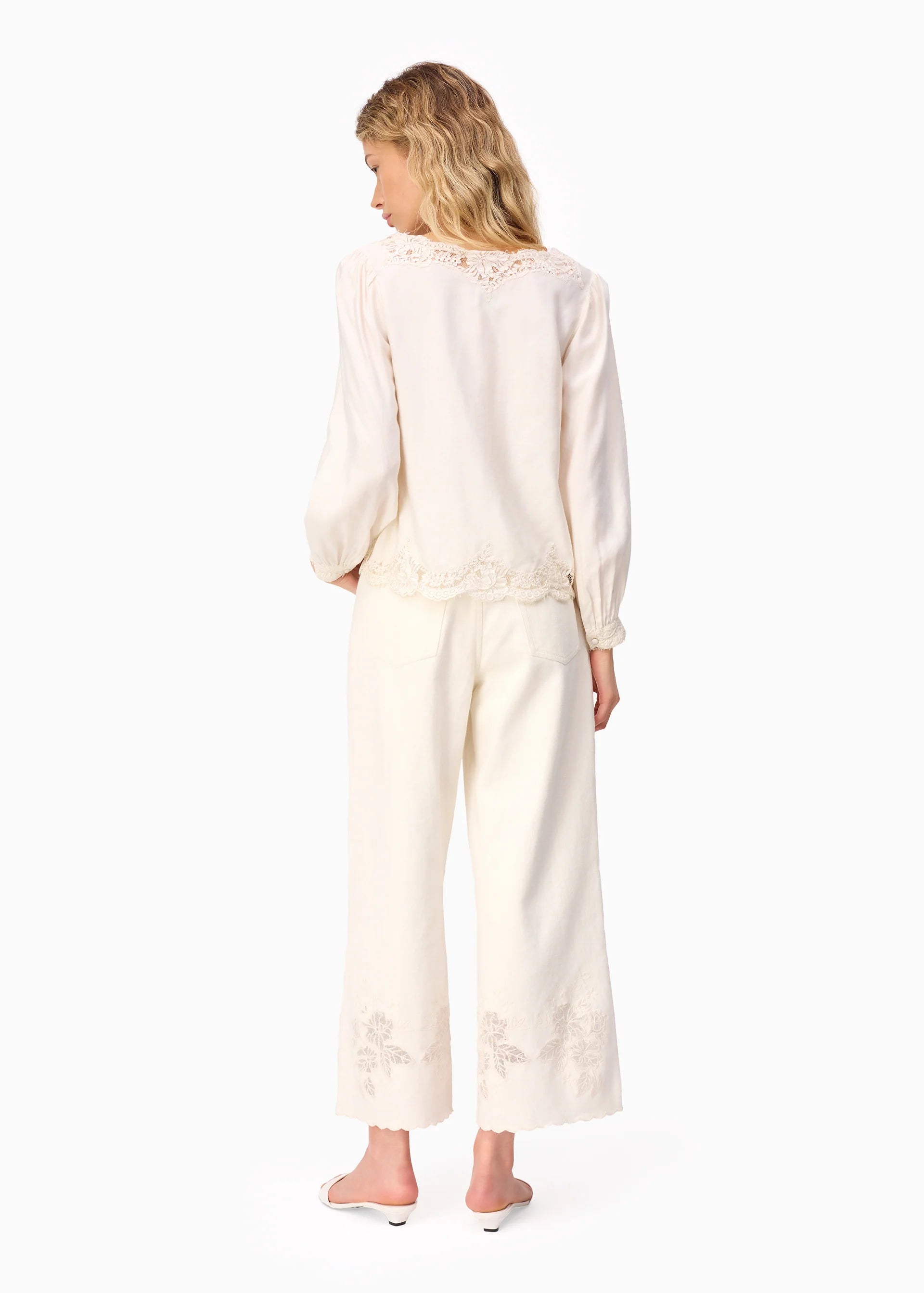 Woman wearing a white outfit with lace details on a white background