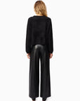 Person wearing a black sweater and black leather pants on a white background, back view