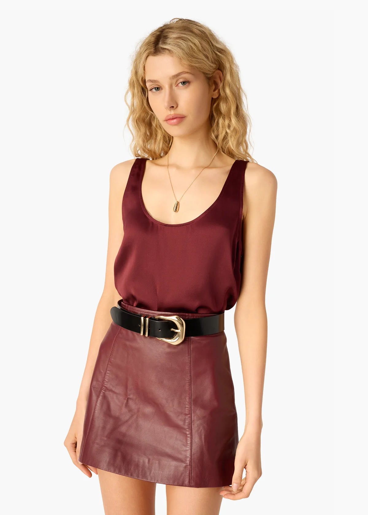 Woman wearing a burgundy sleeveless top and leather skirt on a white background, close up