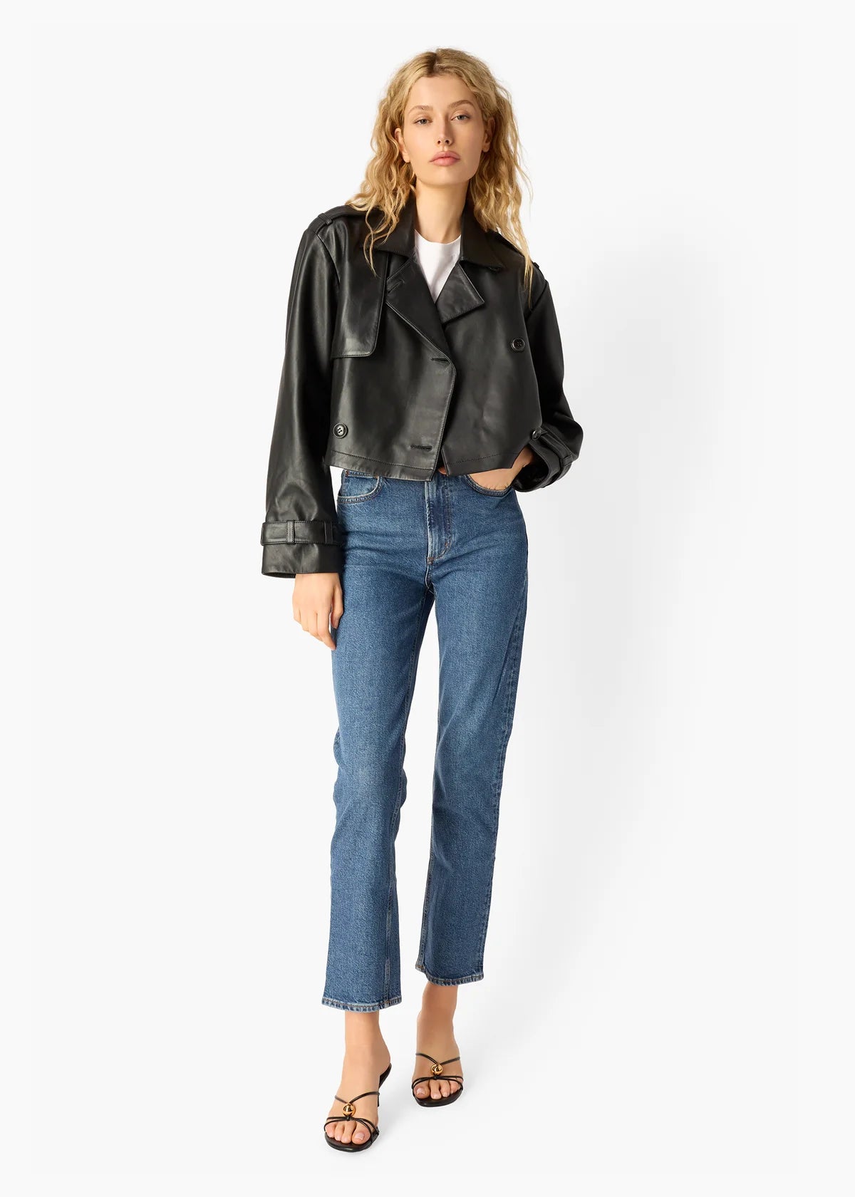 Woman wearing a black leather jacket and blue jeans on a white background, front view
