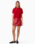 Woman wearing a red t-shirt and red leather skirt on a white background