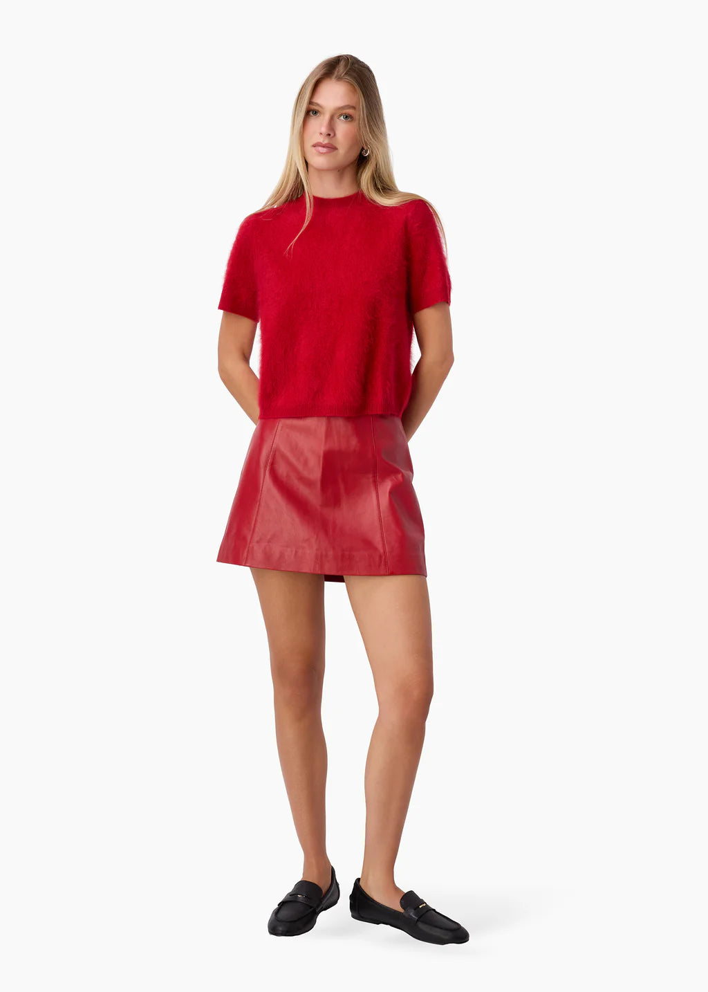 Woman wearing a red top and red leather skirt on a white background