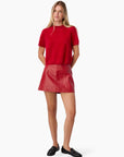 Woman wearing a red top and red leather skirt on a white background