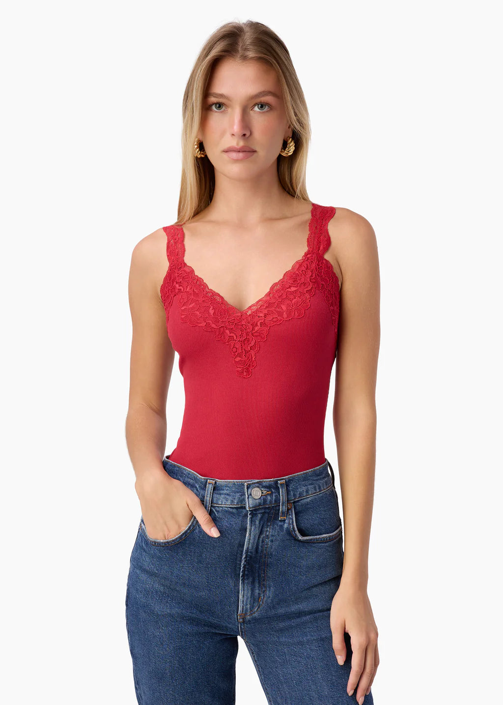 Woman wearing a red lace tank top and blue jeans on a white background