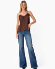 Woman wearing a brown top and blue jeans on a white background