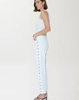 Woman wearing a light blue strapless top and pants with buttons on a white background