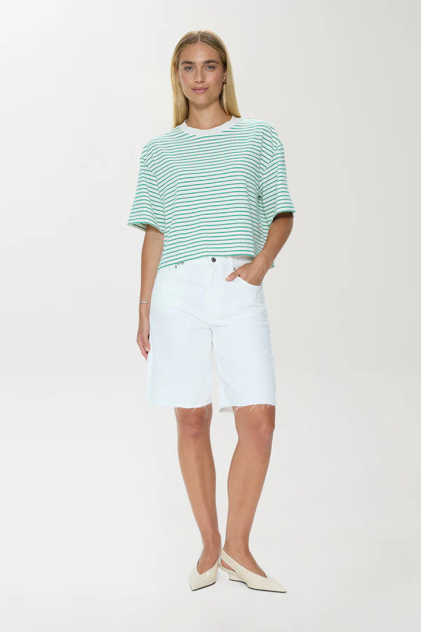Woman wearing a green and white striped shirt and white shorts on a white background