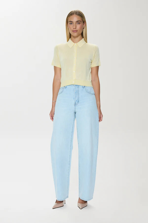 Woman wearing a light yellow blouse and light blue jeans on a white background