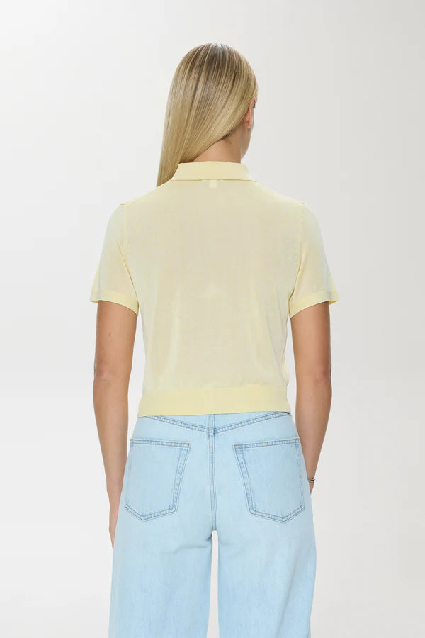 Person wearing a light yellow polo shirt and light blue jeans on a white background