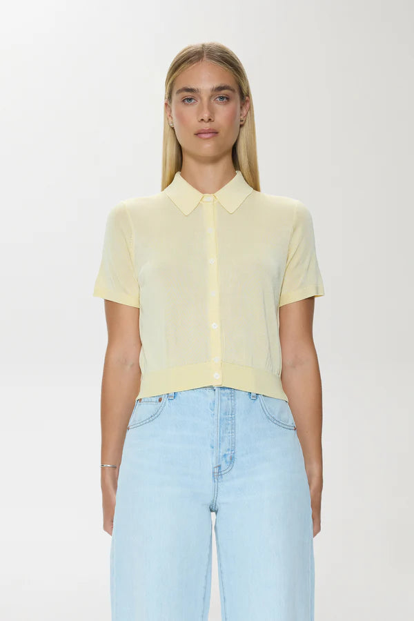 Woman wearing a light yellow shirt and light blue jeans on a white background