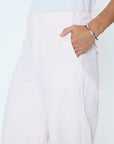 Person wearing light pink pants with a white background