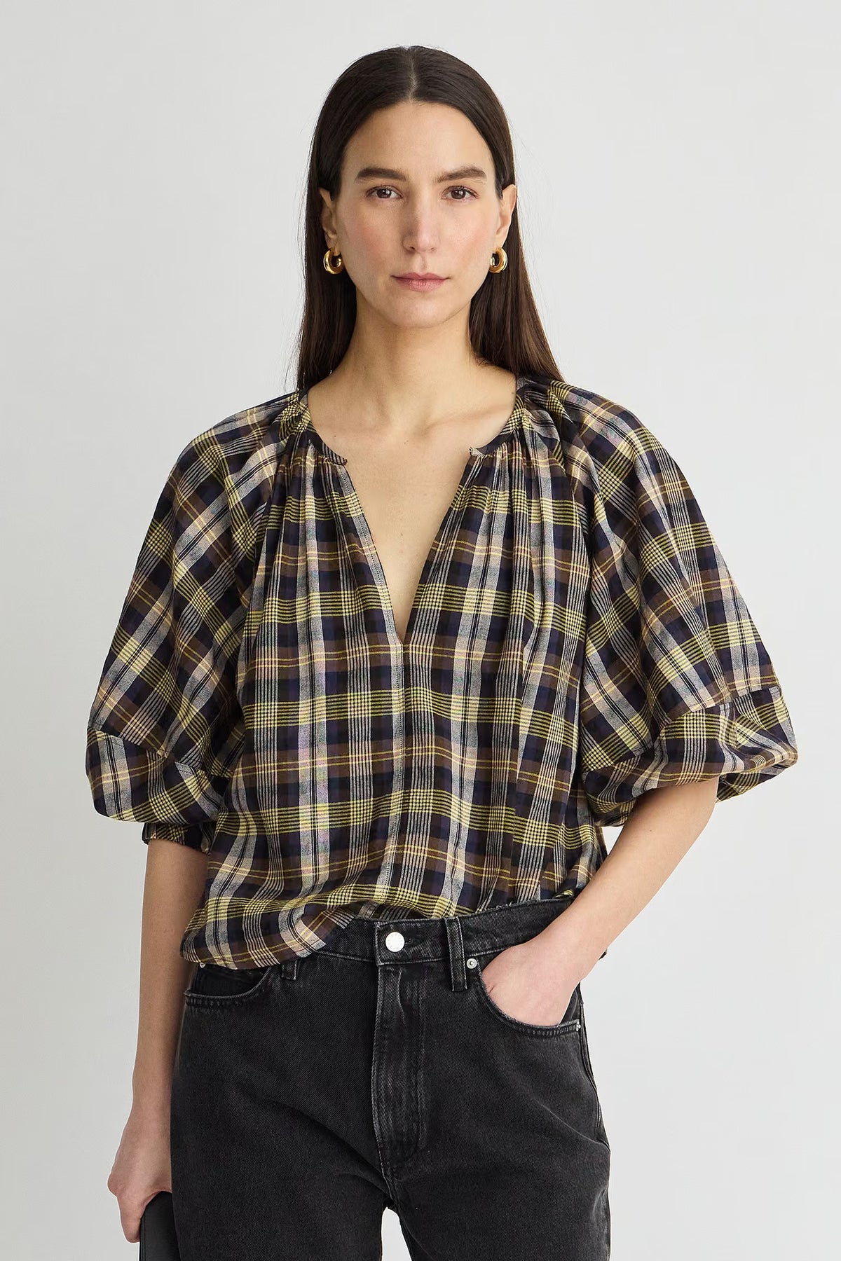 model wearing a plaid vneck short sleeve top with black on a grey background 