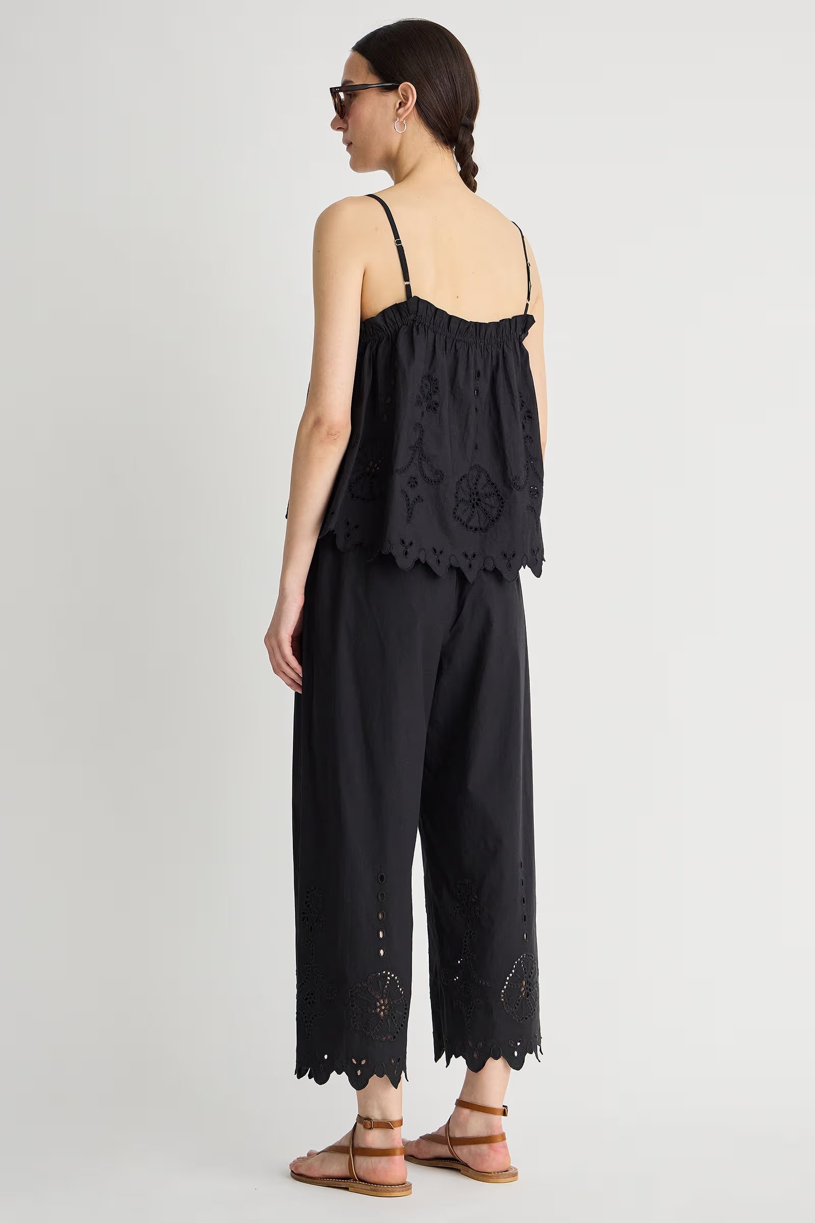 Woman wearing a black lace-trimmed jumpsuit on a white background
