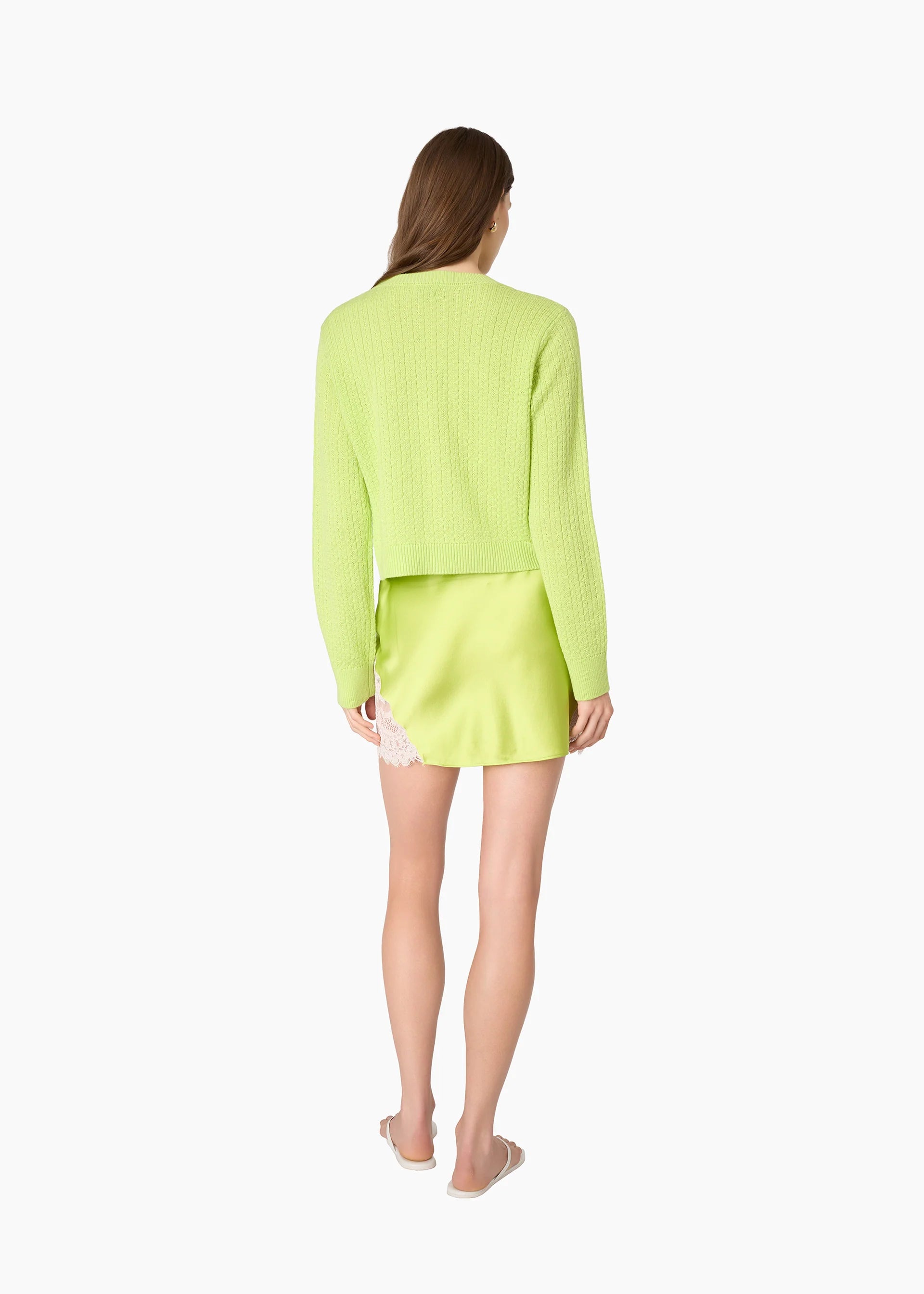 A woman shown from the back wearing a bright neon yellow-green ribbed knit cardigan and matching mini skirt against a plain white background.